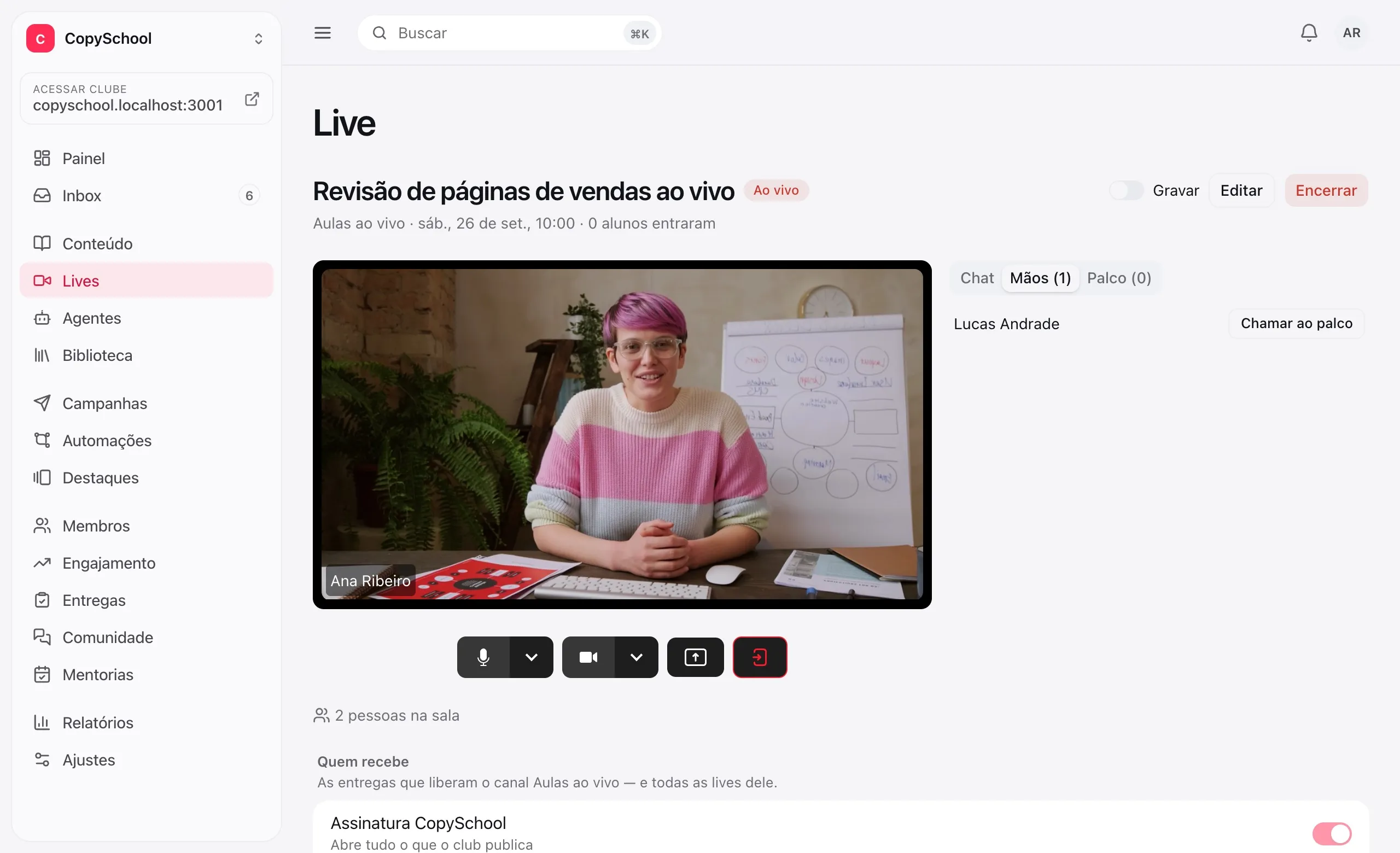 O estúdio de quem apresenta: a câmera ao vivo, os controles e um aluno com a mão levantada, pronto para ser chamado ao palco